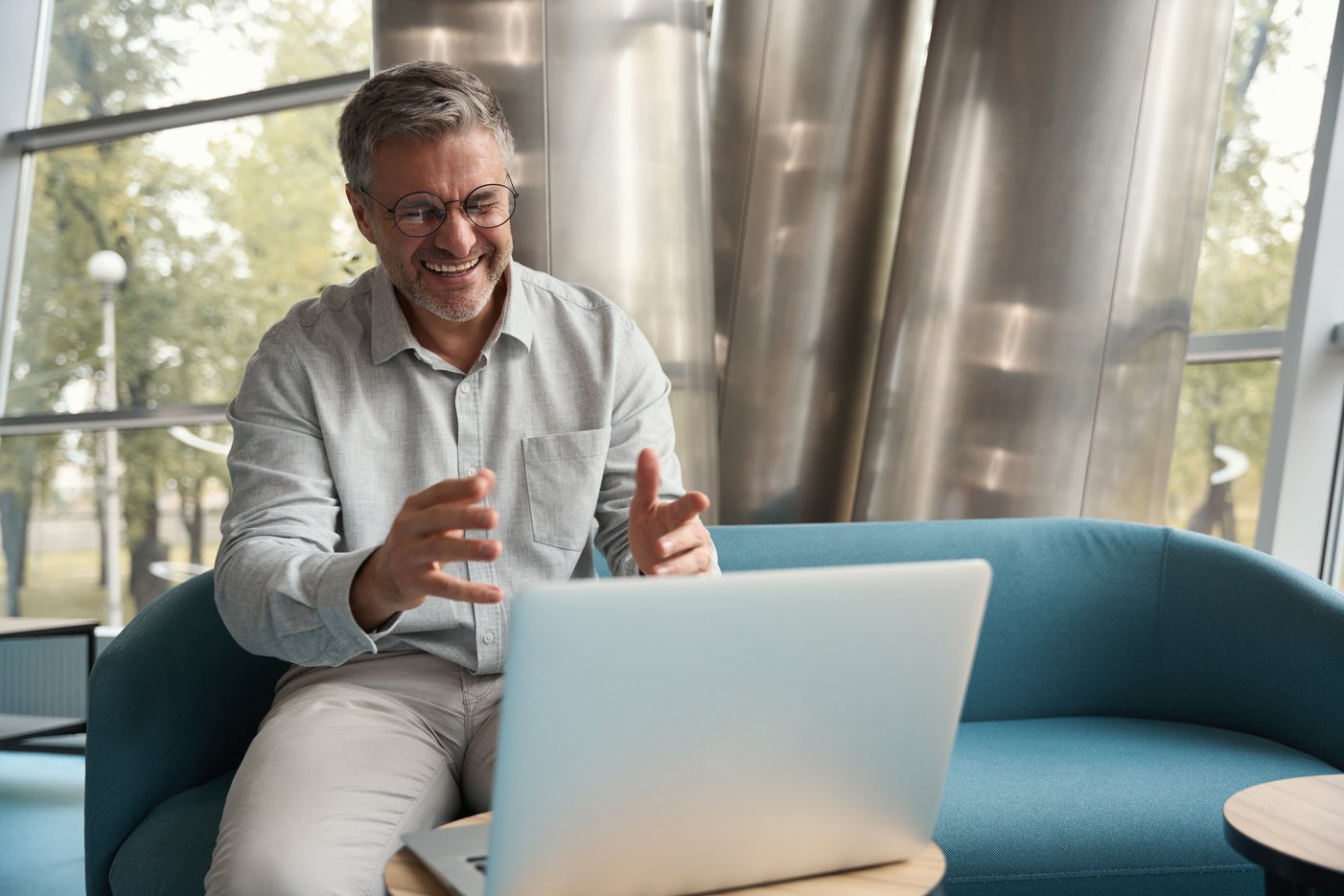 Laughing businessman in glasses communicates online with a subordinate